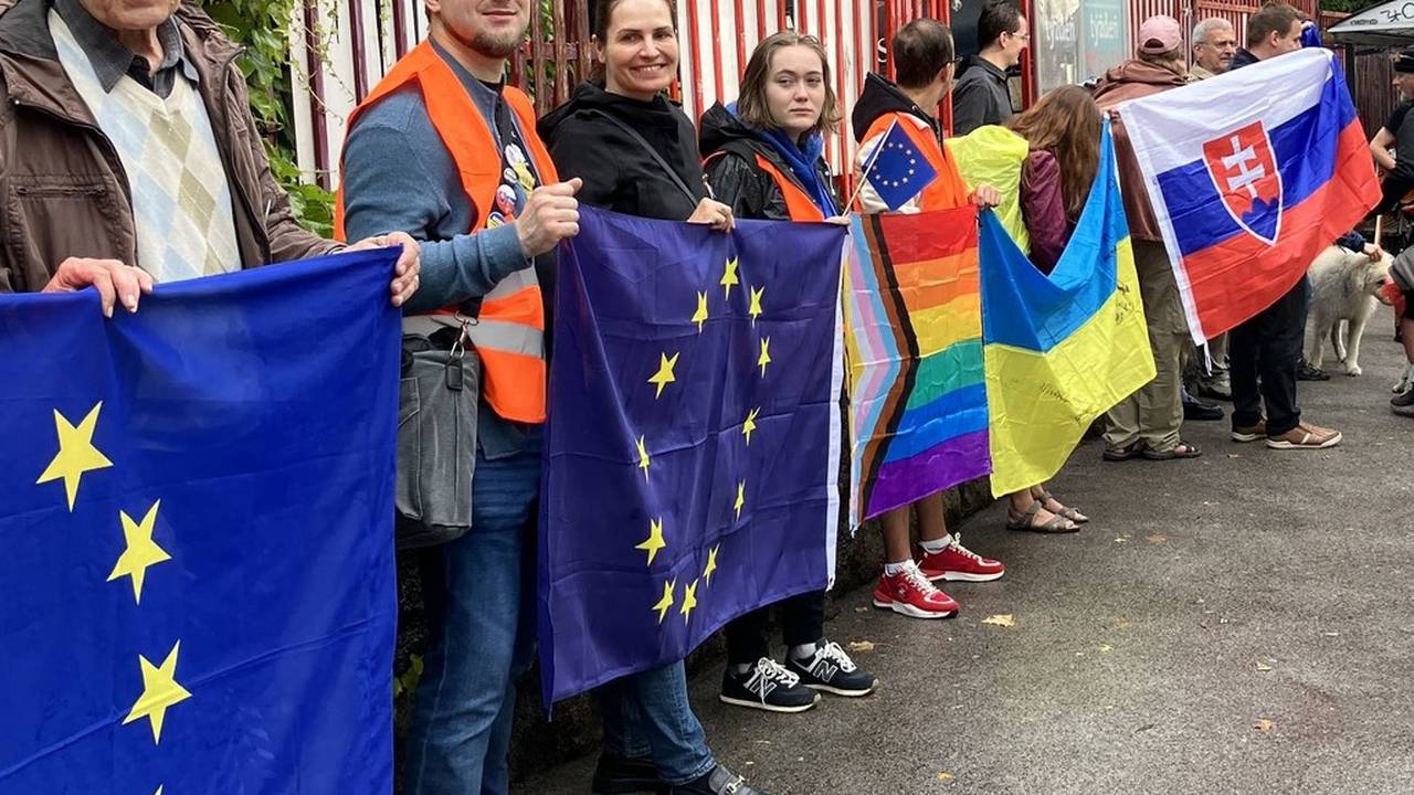 people holding up Slovak, rainbow and EU flags