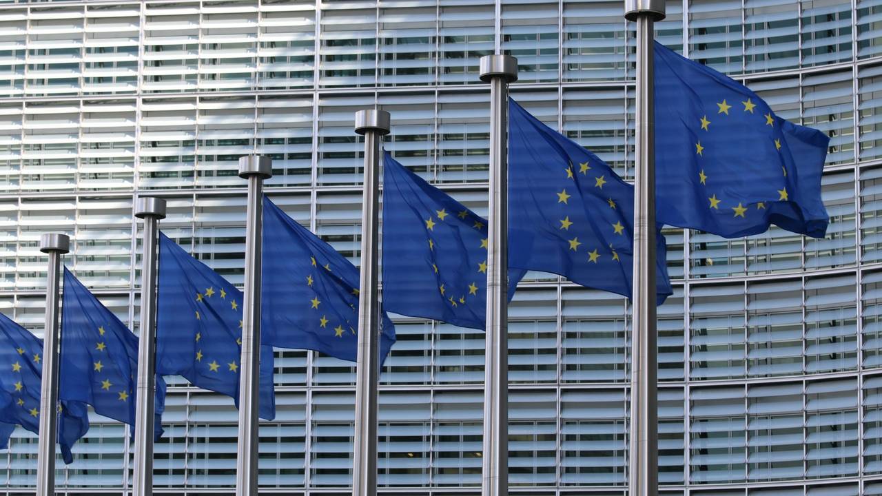A row of EU flags outside the main building of the European Commission