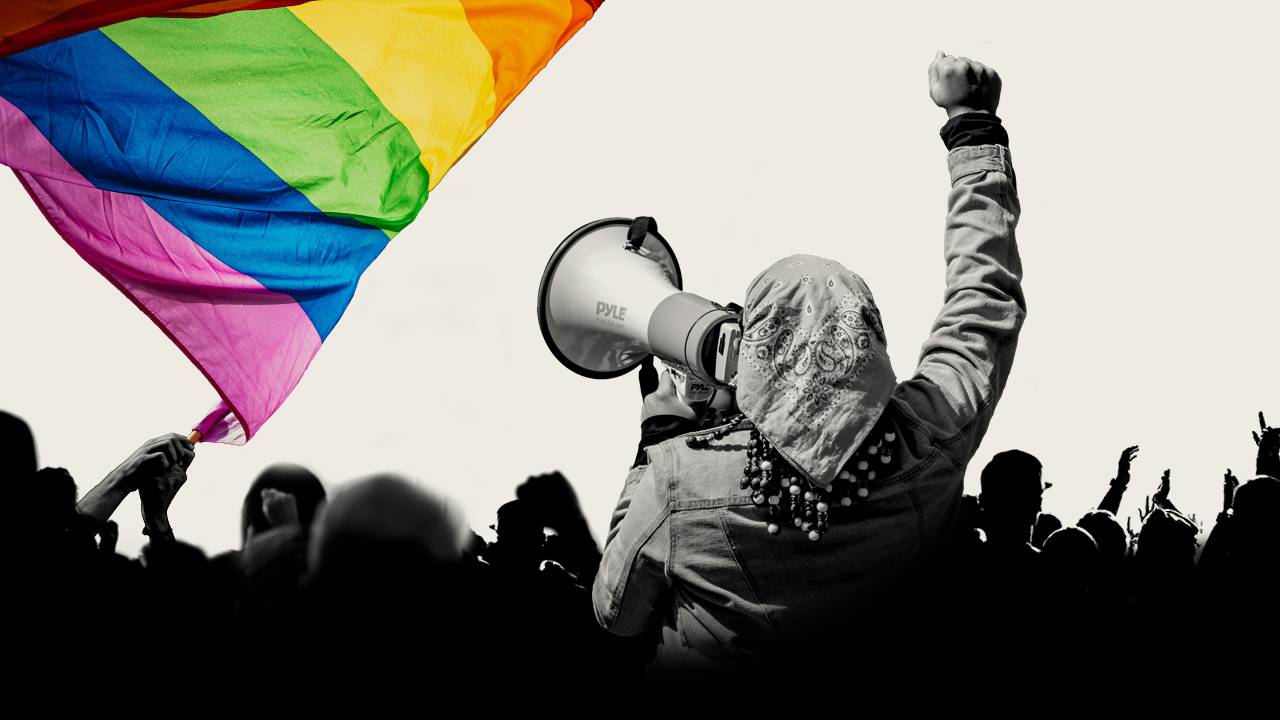 Woman protesting with a LGBT+ flag on the background